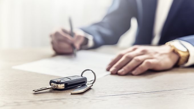 A business owner reviews commercial auto insurance documents and keys lying on a table in an office. 